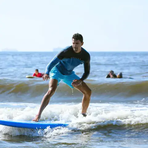 Surfeur debout sur une planche dans les vagues