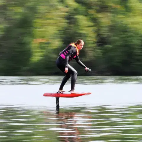 Pilote en vol sur une planche d'e-foil rouge
