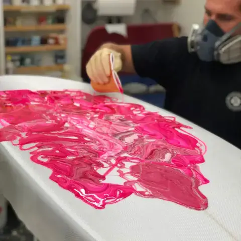Application de résine rose sur le pont d'une planche