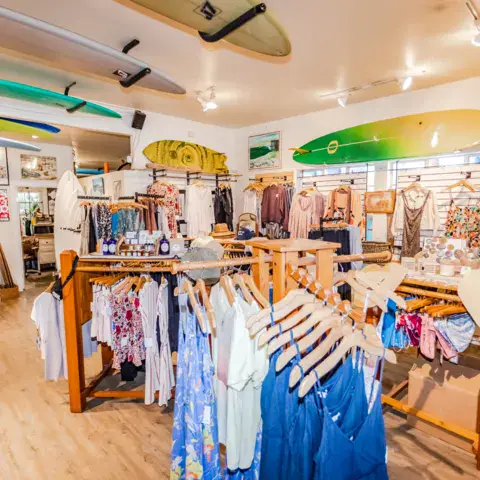 Intérieur du magasin : vêtements et planches de surf accrochées au plafond
