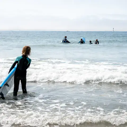 Surfeuse entrant dans l'eau avec sa planche
