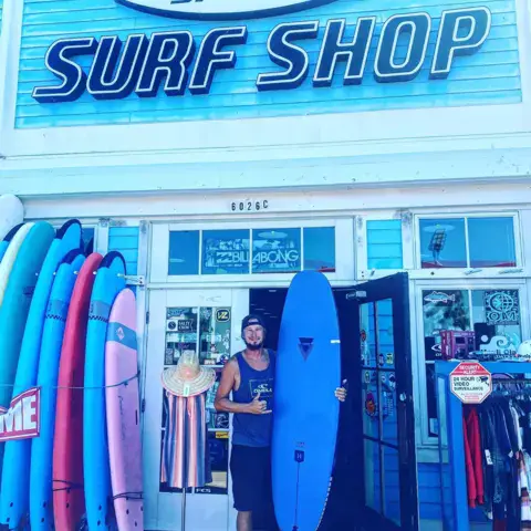 Façade du surf shop avec des planches alignées devant la porte