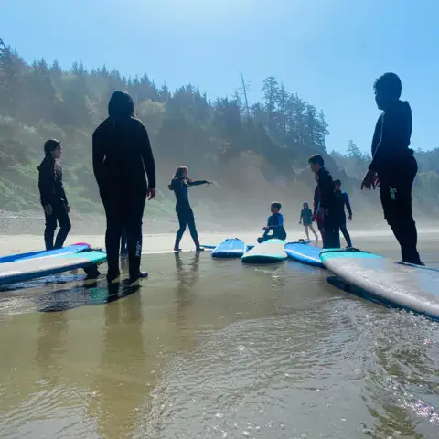Groupe d'élèves avec leurs planches sur la plage