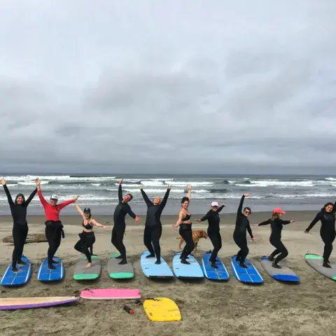 Groupe de surfeurs alignés sur la plage avec leurs planches
