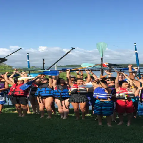 Groupe de participants en gilet, pagaies levées