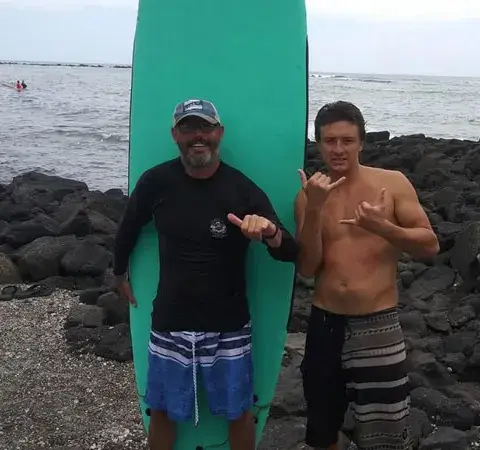 Deux surfeurs devant une planche sur la côte rocheuse
