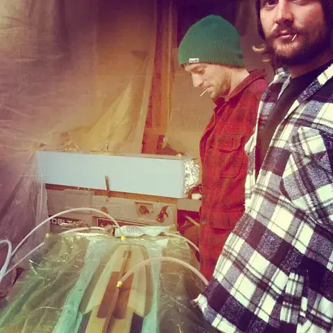 Deux artisans autour d'une planche en cours de fabrication à l'atelier