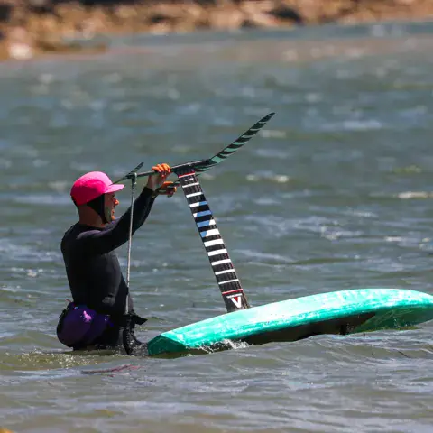 Pratiquante de wing foil dans l'eau avec sa planche