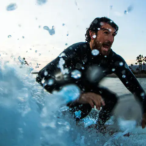 Surfeur sur une vague, éclaboussures au premier plan