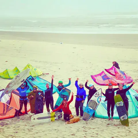 Groupe de kitesurfeuses sur la plage avec leurs ailes et leurs planches