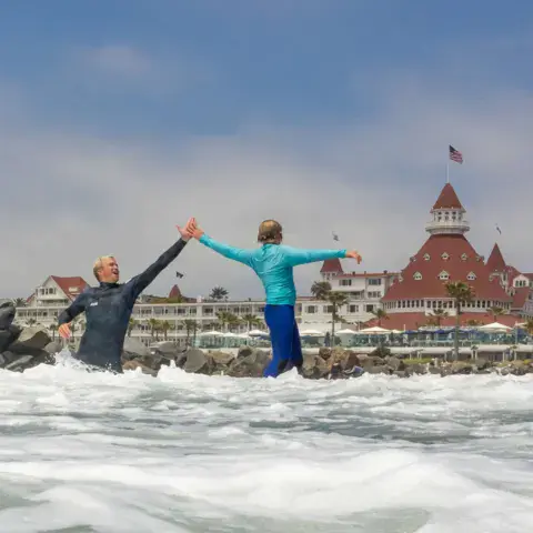 Moniteur et élève sur une vague, hôtel del Coronado en arrière-plan