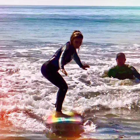 Élève debout sur sa planche dans les vagues