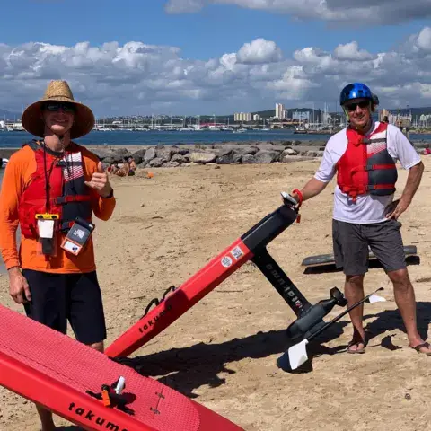 Deux moniteurs avec des planches d'e-foil sur la plage