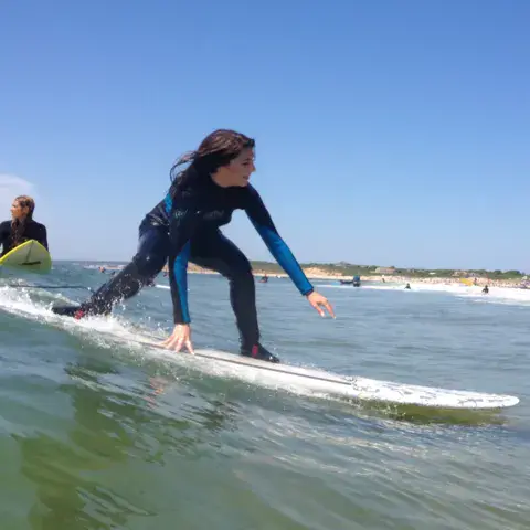 Surfeuse en combinaison glissant sur une vague