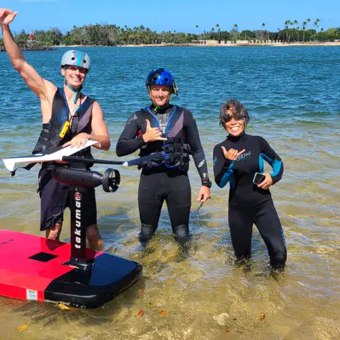 Groupe dans l'eau peu profonde avec une planche d'e-foil