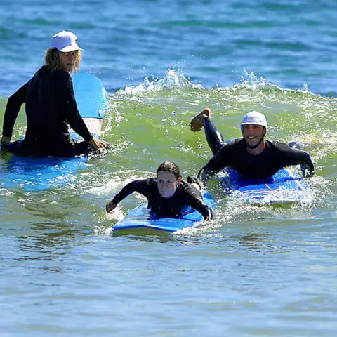 Trois surfeurs allongés sur leurs planches, prêts à ramer dans les vagues