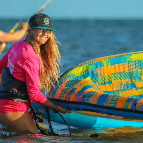 Kitesurfeuse dans l'eau avec son aile colorée