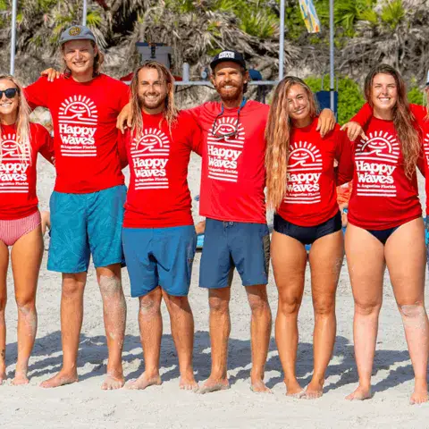Équipe de moniteurs alignés sur la plage en t-shirts rouges
