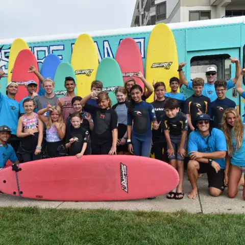 Groupe du stage de surf devant le camion du camp, avec des planches en mousse