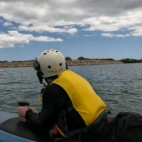 Élève allongé sur sa planche, avec casque et gilet, pendant un cours