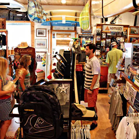 Intérieur du surf shop, avec des clients au rayon vêtements