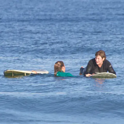 Moniteur et élève sur leurs planches, dans l'eau