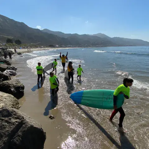 Groupe de stagiaires marchant vers l'eau, montagnes en fond