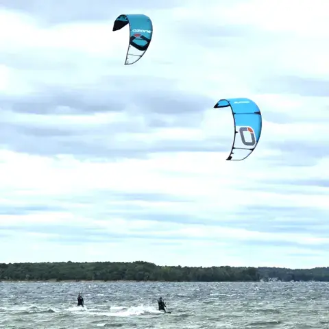 Deux kitesurfeurs sur un lac, par jour de vent