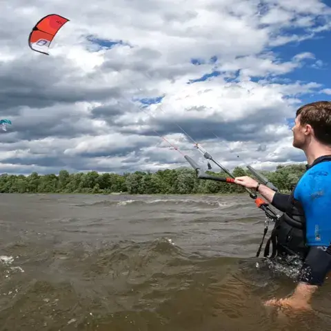 Élève dans l'eau, barre de kite en main, pendant un cours