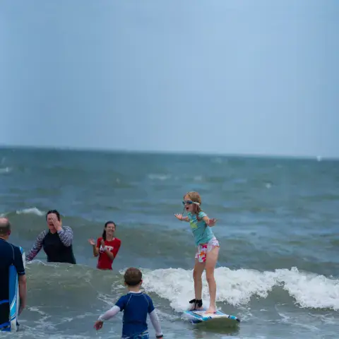 Baigneurs et une surfeuse sur une vague près du rivage