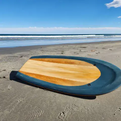 Planche en bois à rail bleu posée sur le sable d'une plage