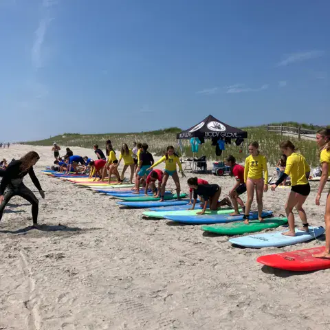 Planches alignées sur le sable et groupe de participants en maillots jaunes
