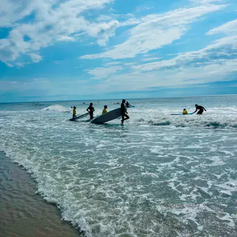 Groupe de surfeurs avec leurs planches dans le shore break
