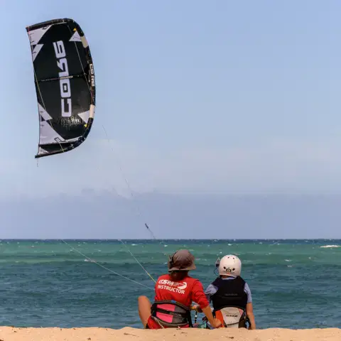 Cours de kitesurf : le moniteur et l'élève assis sur la plage