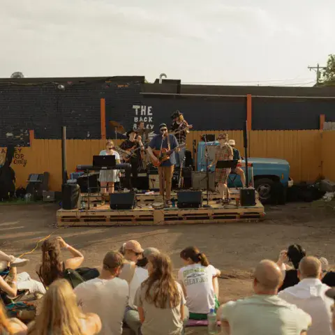 Concert en plein air dans la cour du magasin, public assis devant la scène