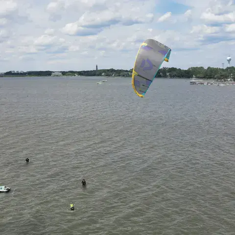 Kite dans le ciel au-dessus du plan d'eau calme, élèves dans l'eau