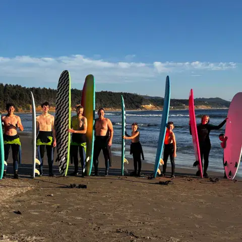 Groupe de surfeurs alignés sur la plage avec leurs planches