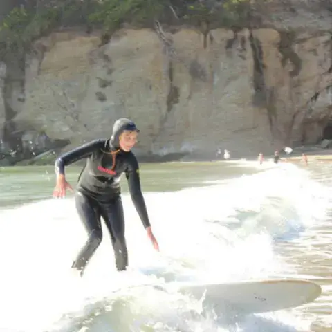 Surfeur sur une vague au pied d'une falaise