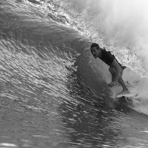 Un surfeur dans le tube d'une vague, en noir et blanc