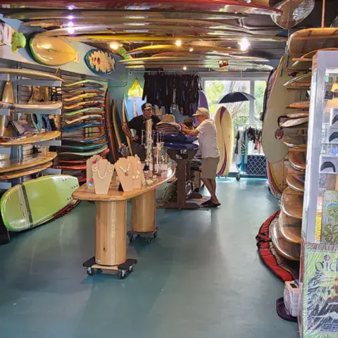 Allée du magasin bordée de planches de surf et de paddle