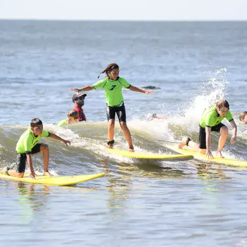 Élèves sur des planches souples jaunes dans les vagues