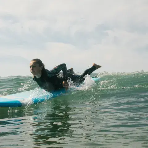 Une surfeuse allongée sur sa planche dans une vague
