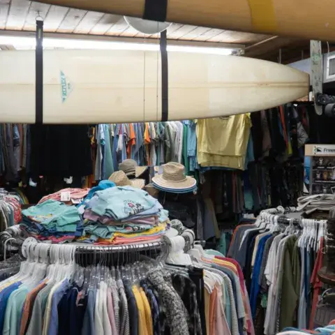 Intérieur du magasin : vêtements et planche de surf