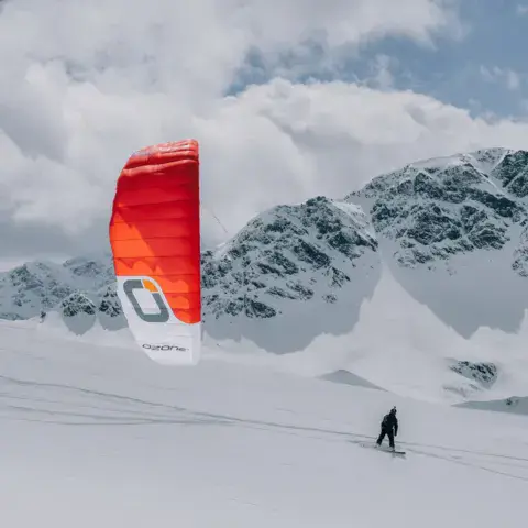 Snowkiter avec une aile rouge devant un paysage de montagne