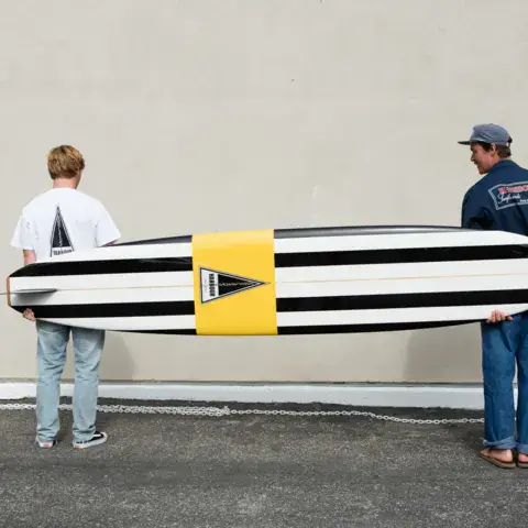 Deux personnes portant un longboard rayé