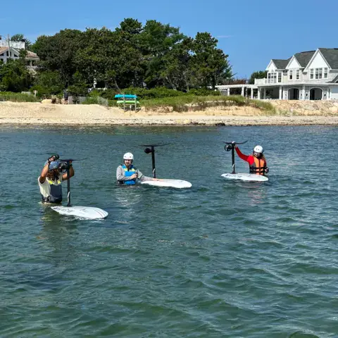 Élèves avec leurs planches de foil dans l'eau peu profonde