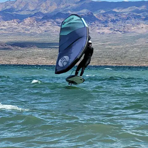 Wing foil sur un lac, montagnes à l'arrière-plan