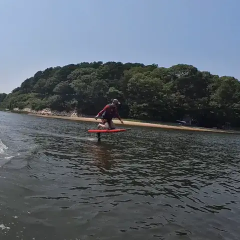 Rider en e-foil devant une côte boisée