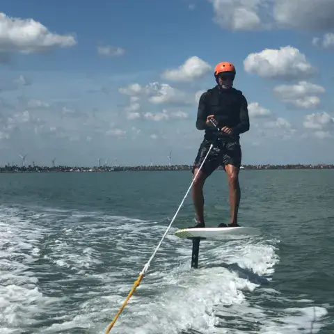 Pratiquant de tow foil tracté derrière un bateau