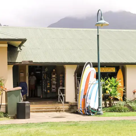 Façade du magasin avec des planches de surf appuyées devant l'entrée